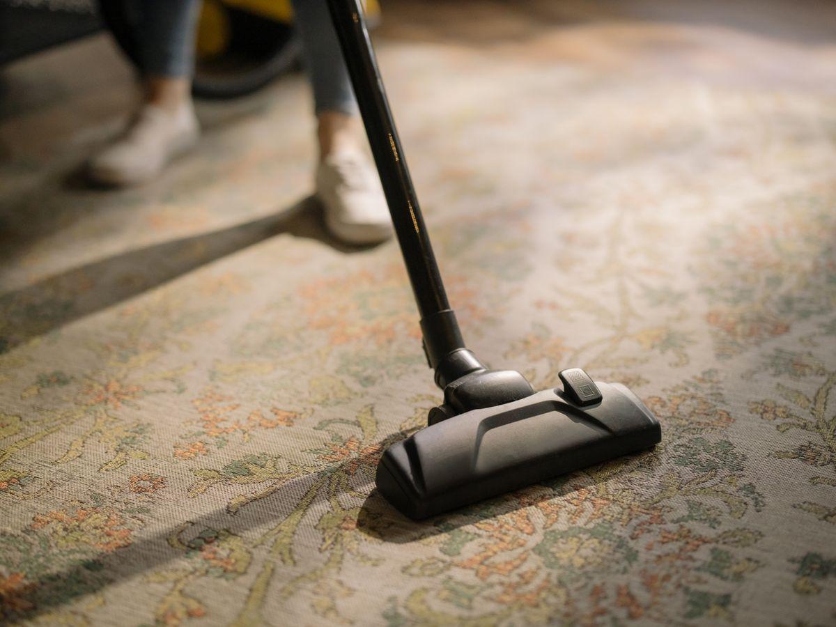 Close-up of a vacuum cleaner head cleaning a patterned carpet